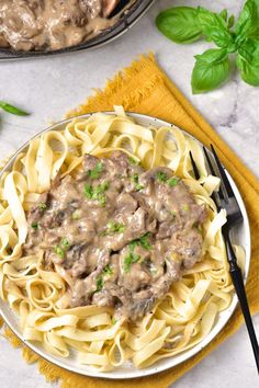 a plate of pasta with meat and mushroom gravy next to a skillet