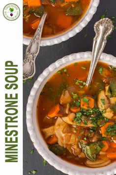 two bowls filled with vegetable soup on top of a black table next to silver spoons