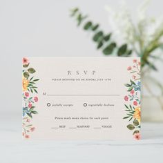 a wedding card with flowers and greenery on the front is displayed next to a plant