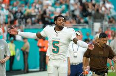 a football player with his arms out in the air as he walks off the field