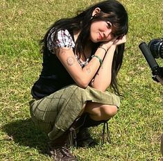 a woman sitting on the ground next to a fire hydrant with her hand near her face