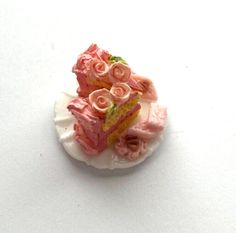 a small piece of cake with pink flowers on it sitting on a white table top