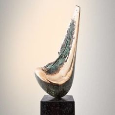 a glass sculpture sitting on top of a wooden block in front of a white wall