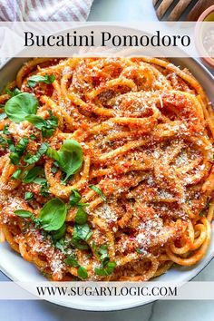 a white bowl filled with spaghetti and basil on top of a table next to other dishes