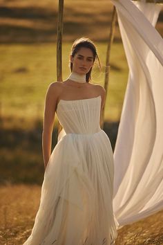 a woman in a white dress is standing outside