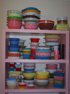 a pink shelf filled with lots of colorful bowls and plates on top of each other