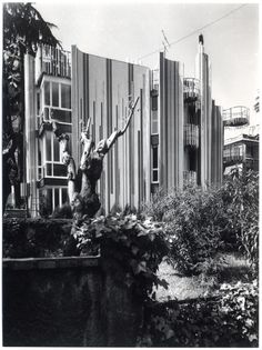 an old black and white photo of a statue in front of a building with many windows