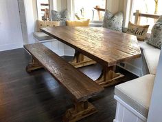 a large wooden table sitting in the middle of a living room next to a window