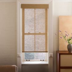 a vase with flowers sitting on a table next to a window in a living room