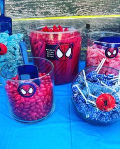 there are some candy and candies in plastic containers with spiderman faces on them