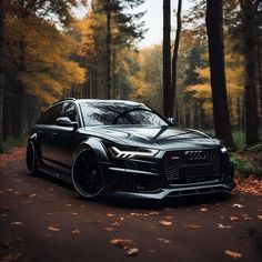 a black car parked in the middle of a forest