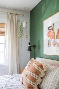 a bedroom with green walls, white bedding and a painting on the wall above it