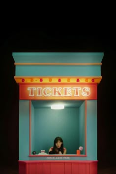 a woman standing in front of a ticket kiosk with the word tickets on it