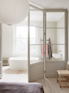 an open door leading to a bathroom with a bathtub and chair next to it