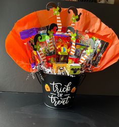 a trick or treat bucket filled with candy and candy bar wrapper decorations on top of a table