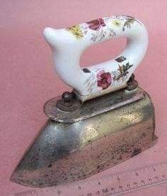 an old iron with flowers painted on it sitting next to a measuring tape and ruler