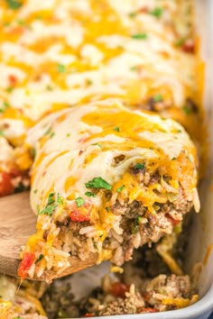 a casserole dish with meat, cheese and vegetables being lifted from the casserole