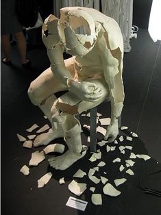 a white sculpture sitting on top of a chair covered in pieces of torn up paper