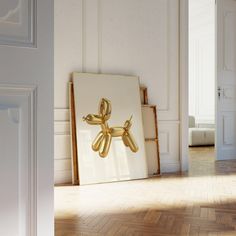 a golden balloon dog sitting on top of a wooden floor next to an open door