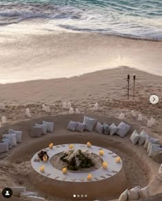 an outdoor seating area on the beach with candles and flowers set up in the sand