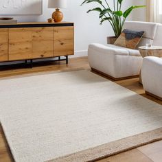 a living room with two white couches and a large rug