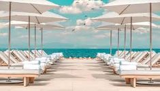 rows of lounge chairs and umbrellas with the ocean in the background