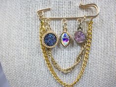 three different colored jewels are attached to a gold chain