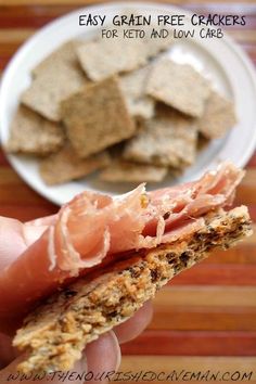 a person is holding up a cracker with some food in the background