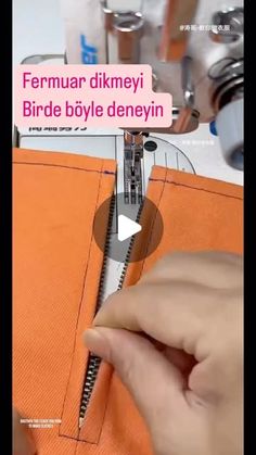 someone is using a sewing machine to sew the zippers on an orange piece of fabric