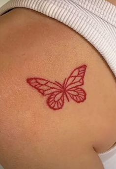 a woman's stomach with a red butterfly tattoo on the side of her belly