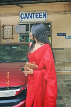 a woman standing in front of a red car