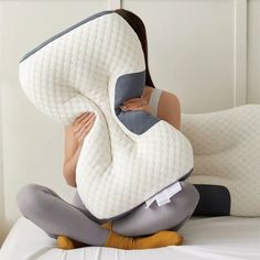 a woman sitting on top of a bed with a pillow over her face and arm