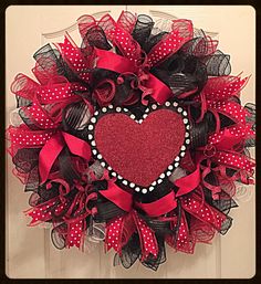 a red and black mesh wreath with a heart on the front door, decorated with polka dots