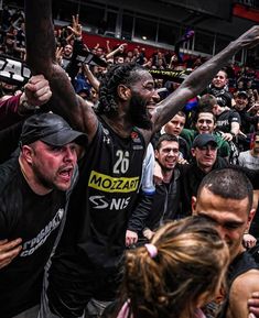 a group of men standing next to each other on top of a basketball court in front of a crowd