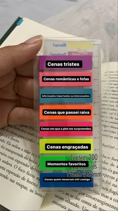 a hand holding a stack of multicolored stickers on top of an open book