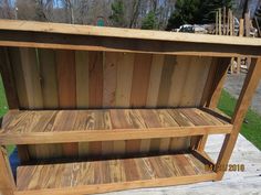 a wooden shelf sitting on top of a wooden deck next to a green grass covered field