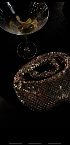 a snake skin purse sitting on top of a table next to a glass filled with liquid