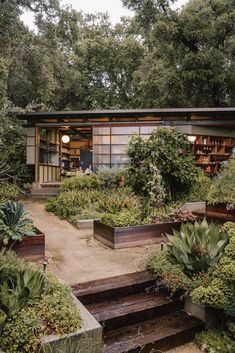 an image of a small house in the middle of some trees and bushes with plants around it