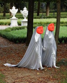 two plastic ghost statues in the middle of a park