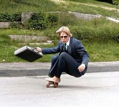 a man riding a skateboard down a street holding a briefcase in his right hand