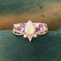 an opal and diamond ring on top of a green surface