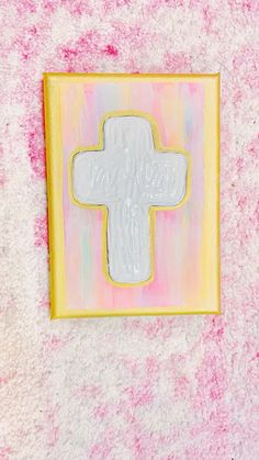 a cross painted on the side of a pink and yellow wall next to a painting