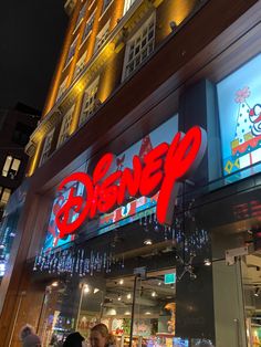 people walking in front of a disney store at night