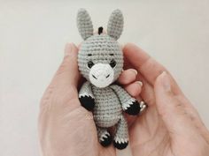 a hand holding a tiny crocheted animal in it's right hand,