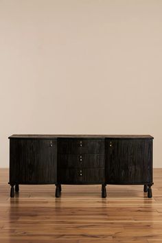 two black dressers sitting on top of a hard wood floor next to a white wall