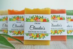 four soap bars sitting on top of a wooden table next to an orange and green leaf