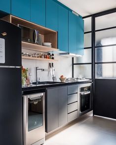 a modern kitchen with stainless steel appliances and blue cabinetry, along with black countertops