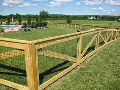 a large wooden fence in the middle of a grassy field with a pool behind it