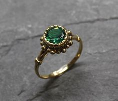 Gold Emerald Ring set with a Created Emerald in a perfect diamond cut, flawless clarity & deep green color, at 8mm diameter, weighting 2 Carats. Round Vintage Ring design made of Gold Vermeil ☞ thickest 18k Gold Plating on top of Solid 925 Sterling Silver ☞ made to last.☞ Choose your size ☞ I resize (before shipping) for FREE to Any size*Matching Earrings: www.etsy.com/listing/1056117887Matching Pendant - please ask me⌛Last Ring left ⌛ Details : ♥ Each item comes in a cute GIFT BOX ✓♥ GUARAN Heirloom Green Diamond Ring With Bezel Setting, Green Emerald Crystal Ring, Green Bezel Set Rings For May Birthstone, Green Rings With Bezel Setting For May Birthstone, Vintage Green Diamond Ring Gift, Fine Jewelry Round Flower Ring With May Birthstone, Green Rings With Halo Setting, Green Halo Setting Ring With Round Band, Green Halo Setting Promise Ring