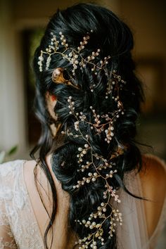 the back of a woman's head wearing a bridal hair piece with flowers and pearls